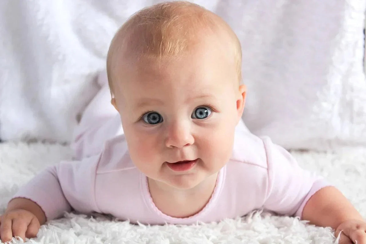 Smiling baby lying on her tummy looking at the camera