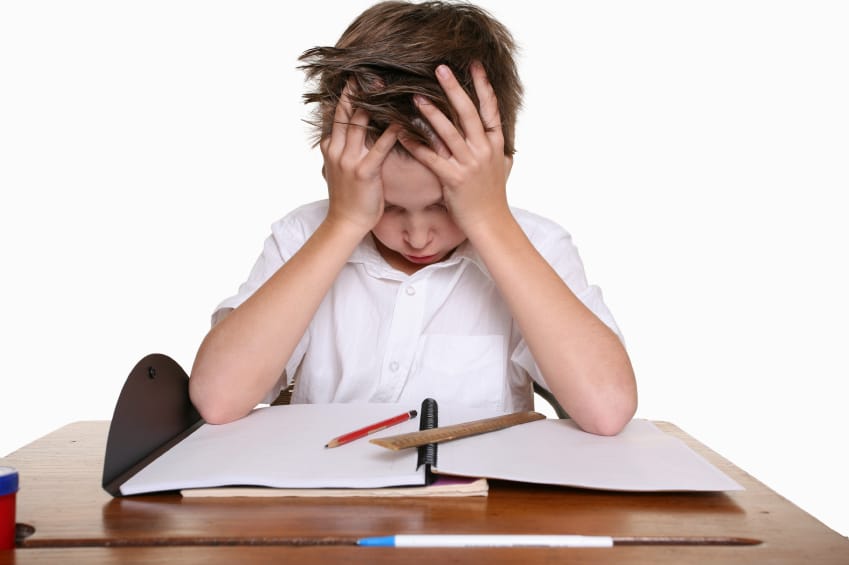 Young boy holding his head in frustration over his schoolwork