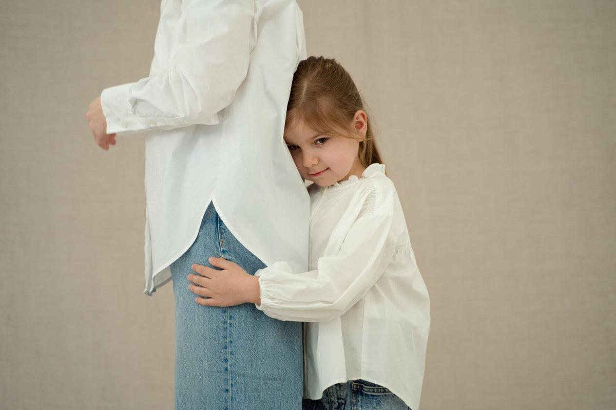 Shy little girl hugging her parent's leg